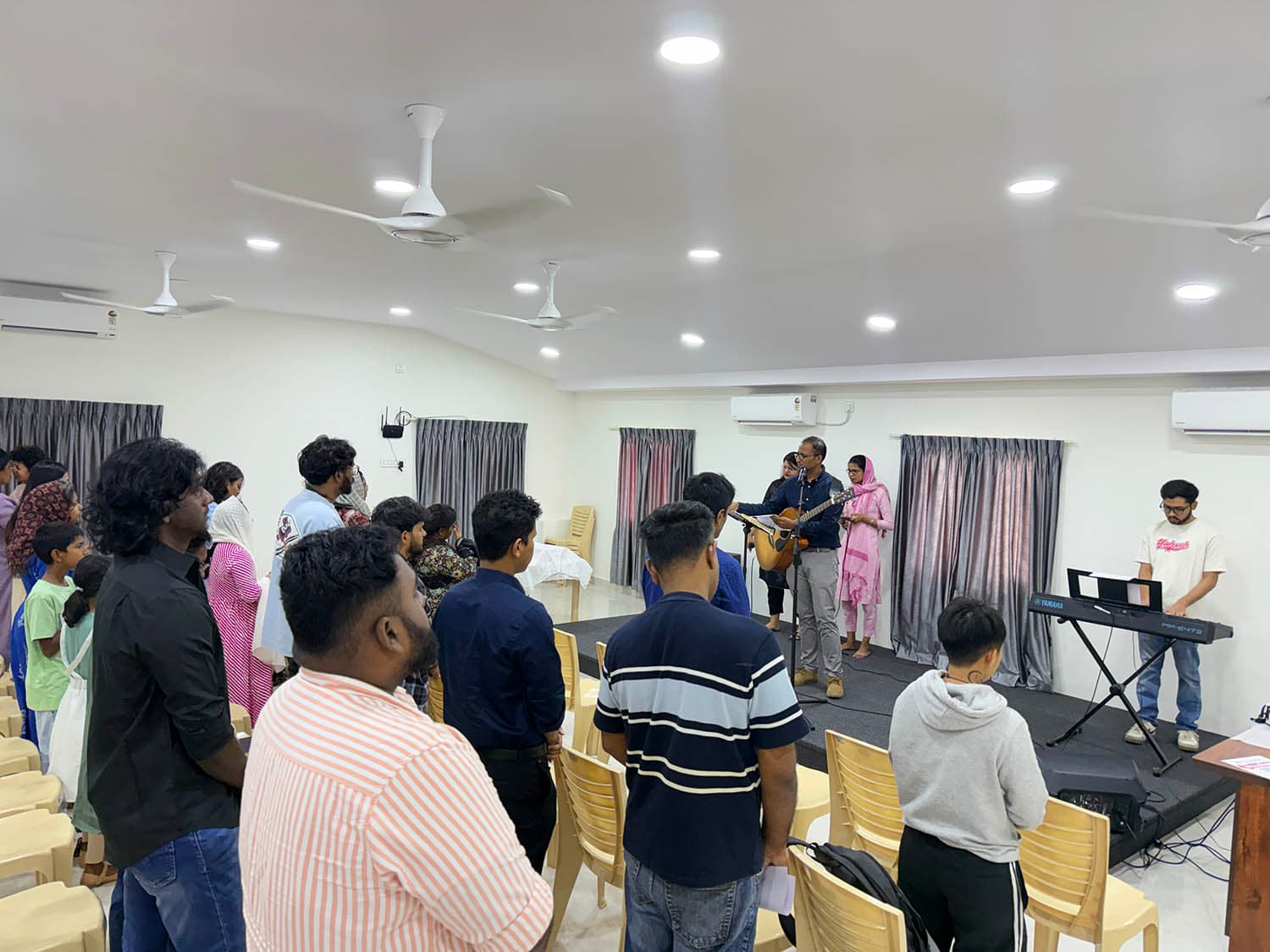 The congregation standing together as the worship team leads a song